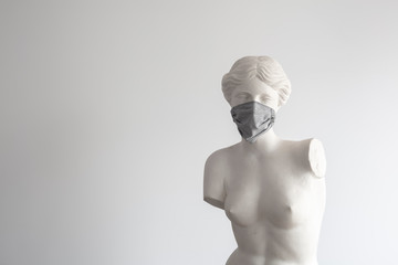 Statue of the goddess Aphrodite with face mask in white background