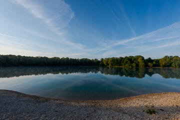 Fototapeta na wymiar Small local recreation swimming lake in Bavaria, Germany in early morning light with fog over water