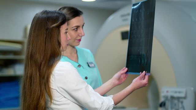 Female doctors examine x-ray in modern clinic. Two women specialists looking at radiographic image and making diagnosis.
