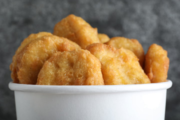 Bucket with tasty chicken nuggets on grey background, closeup