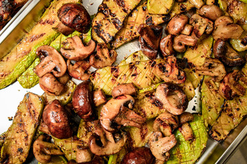 Close-up of top view on metal tray with grilled zucchini and mushrooms