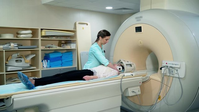 Medical scanning equipment and a female patient. Doctor preparing patient before the mri procedure. Woman lays in magnetic resonance image device.