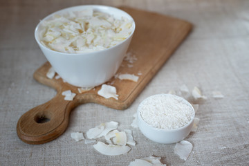 Coconut chips and shavings in a bowl on a cloth tablecloth and cutting board