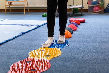 
Pediatric Sensory Integration Therapy - a child walking on a sensory mat and pillows (close-up picture)