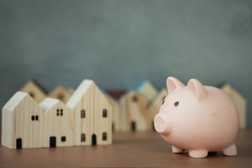 Miniature wooden houses and pink piggy bank