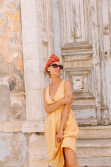 Pretty young female tourist posing in front of beautiful door in the centre of old mediterranean town, her hairstyle enhanced by turban