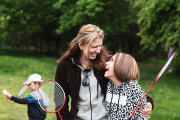 Happy mom and daughter play badminton together, hug each other and laugh sincerely, the real...