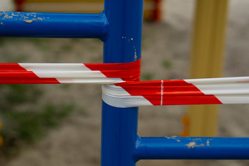 Red warning tape at the playground for children during the quarantine COVID-19. Quarantine restrictions to prevent infection contamination.