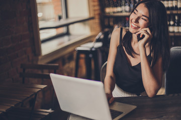 Business woman working on a laptop and using phone in a cafe.