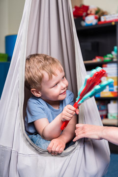 Pediatric Sensory Integration Therapy - boy swinging and playing a musical instrument