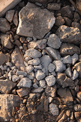 gray stones lie on the ground, yellow sunset light, textural natural background