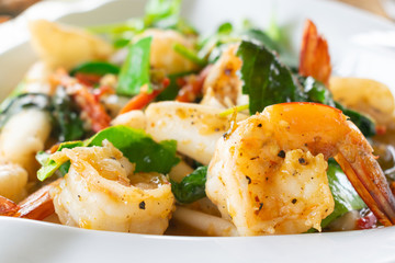 Closeup of Spicy fried seafood with shrimp in white dish.