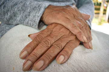 Fototapeta premium The hand of the sick old woman rests on the lap. Mental health care at home.