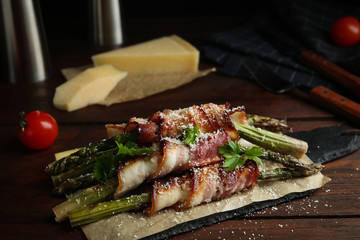 Oven baked asparagus wrapped with bacon on wooden table