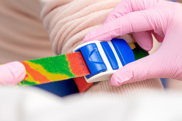 Close up of hand of doctor or nurse tightening tourniquet or strap on the arm before blood sampling.