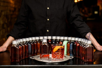 glass of negroni cocktail with many bottles stands on bar.