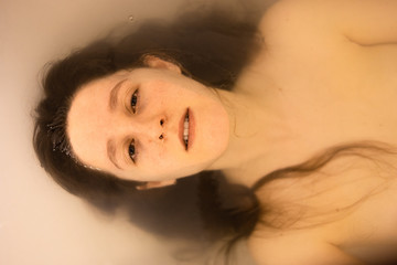 portrait of girl in the bathtub, serious, lonely, half submerged
