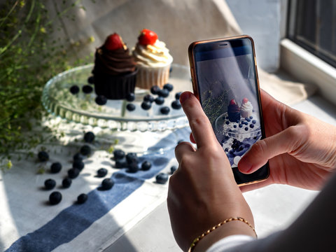 female hands take pictures of cake on the phone
