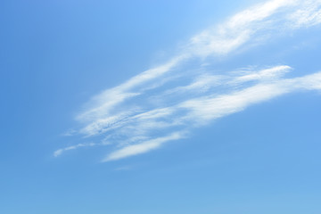 Llight translucent cirrus cloud high in the blue sky. Separate fibers and denser areas are clearly visible. Cloud formation and atmospheric phenomena.