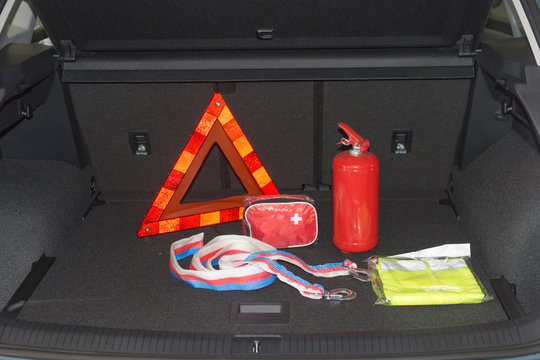 Travel kit in the trunk of a car. Fire extinguisher, tow rope, warning triangle, medical kit, reflective vest.
