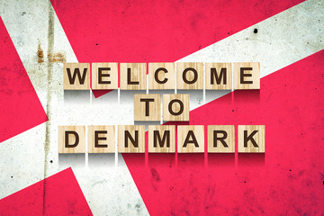 Welcome to Denmark. The inscription on wooden blocks on the background of the flag of Denmark.