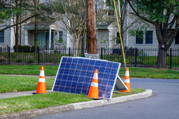 Cracked solar panel on the ground near a utility pole that they fell from with orange warning cones...