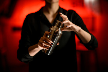 Close-up. Metal shaker in hands of female bartender.