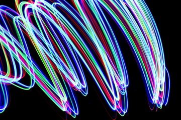 Long exposure photograph of neon colour in an abstract swirl, parallel lines pattern against a...