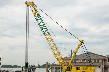 High yellow crane on the construction site on the river.