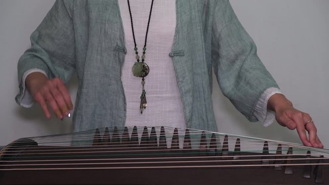 Young woman learn Chinese music instrument Guzhen at home amid coronavirus pandemic