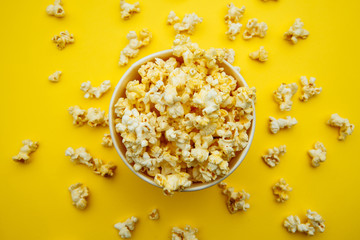 Fototapeta na wymiar Bowl with popcorn on yellow background. Top view. Entetainement concept.
