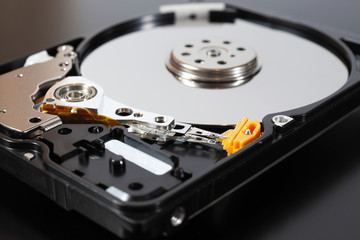 A disassembled open hard disk drive HDD of a computer or laptop lies on a dark matte surface....