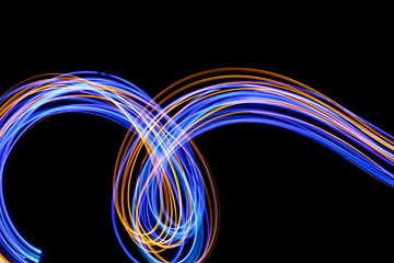 Long exposure photograph of neon blue and gold colour in an abstract swirl, parallel lines pattern against a black background. Light painting photography.