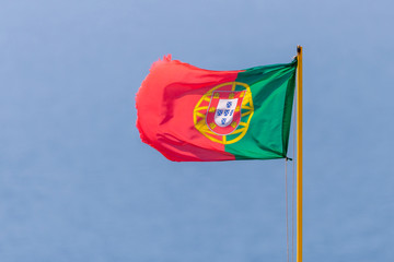 Flag of Portugal waving, against blue sky