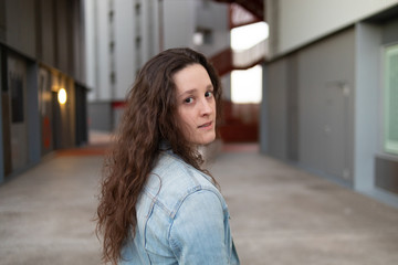 portrait of a girl in denim clothes with a building with red stairs in the background
