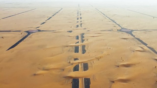 STUNNING AERIAL SHOT of a cluster of abandoned roads in the middle of the desert in Dubai, United Arab Emirates. Tilt up aerial shot of abandoned roads covered in sand in Dubai. 