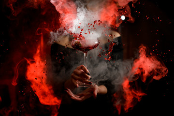 view of glass with steaming and splashing cocktail in woman's hand