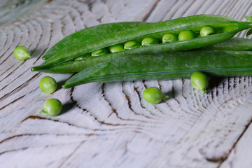Food background. Green pods of young peas on a light wooden table. Close-up of green peas. Side view, close-up, free space below, nobody.