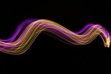 Long exposure photograph of neon pink and gold colour in an abstract swirl, parallel lines pattern against a black background. Light painting photography.