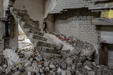 A broken concrete staircase with a pile of broken bricks and construction debris inside the...