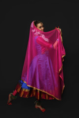 Girl dancer of Indian dances. A woman in an Indian suit. Portrait on a black background.