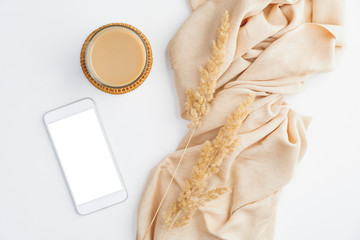 Modern minimal home office desk with beige blanket, cup of coffee, dry flowers and smartphone with...