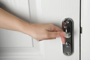 Naklejka premium Woman opening white wooden door indoors, closeup