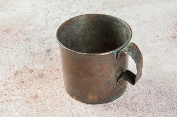 Old brass mug with handle on concrete background