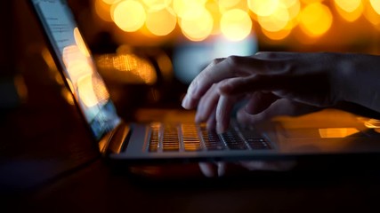 Typing text on laptop pressing buttons. Female writer creating her new bestseller book with great inspiration. Yellow lights bokeh. 4K