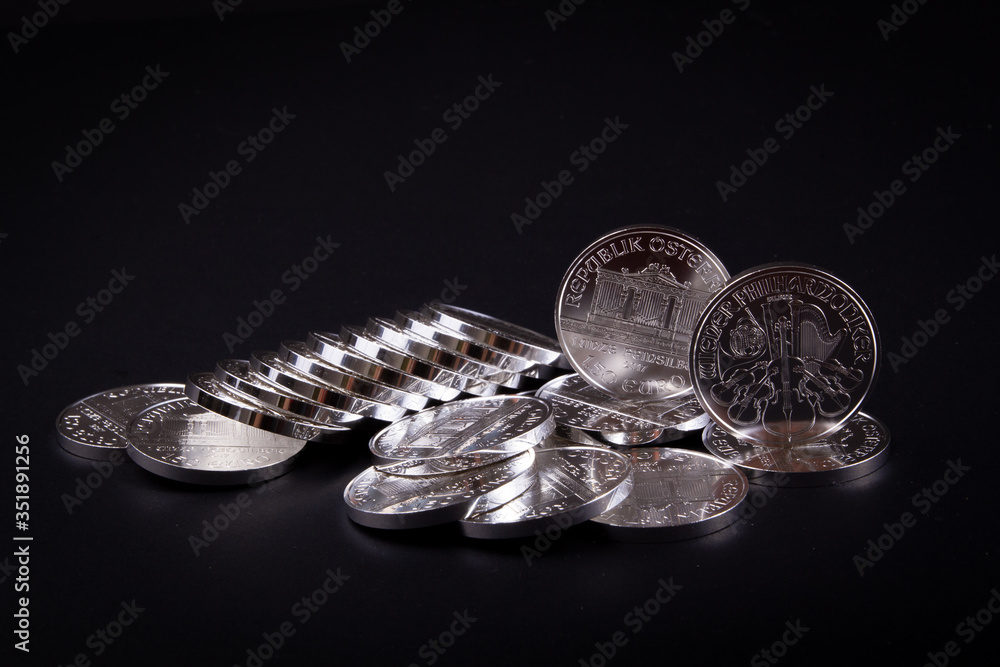 Wall mural Investment silver fine bullion coins, secure means to preserve wealth during crisis. Physical silver coins on black background. Silver price market.