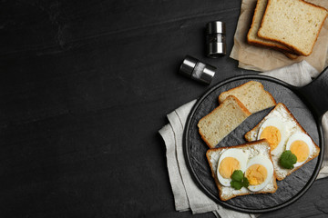 Tasty sandwiches with boiled eggs served on black table, flat lay. Space for text