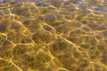 Fototapeta na wymiar through the clear water with Sunny highlights you can see the sandy bottom of the river