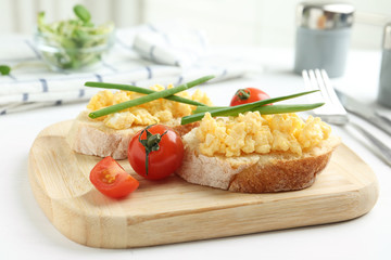Tasty scrambled egg sandwiches on white wooden table