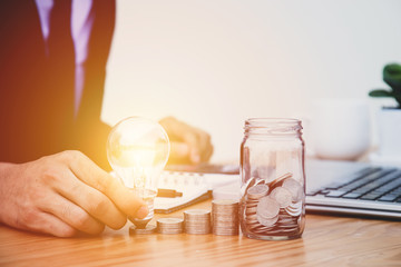 Business man hand holding lightbulb with money stack. concept idea saving finance.